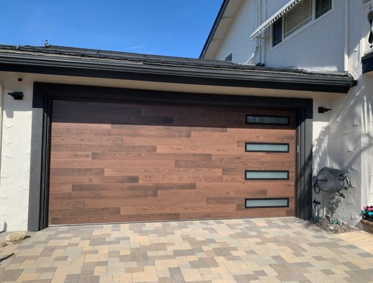 Wood-look garage door with window strips above a paver driveway